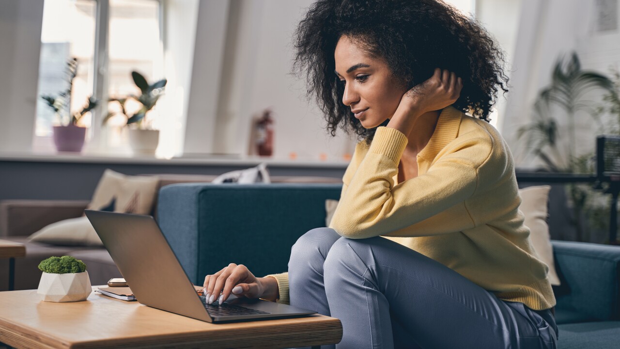 Woman working at a laptop, sitting on couch