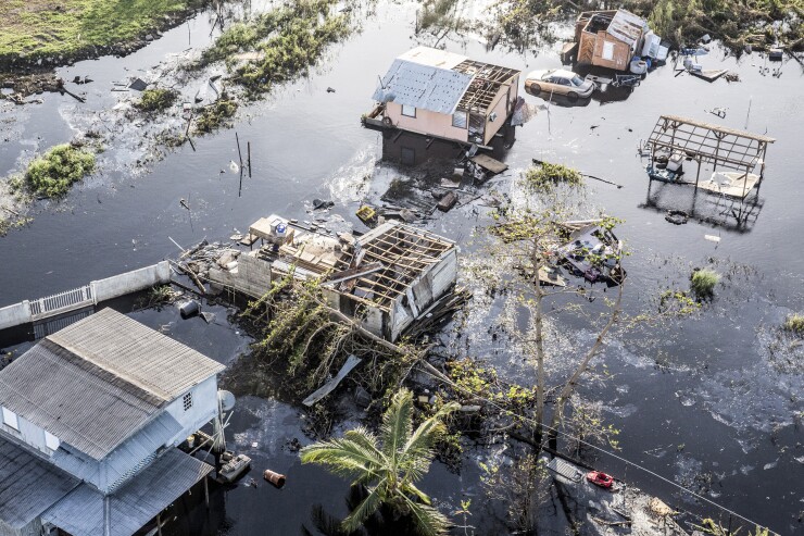 Destroyed homes and vehicles sit in floodwaters after Hurricane Maria Hamacao, Puerto Rico, on Monday, Sept. 25, 2017 Bloomberg News