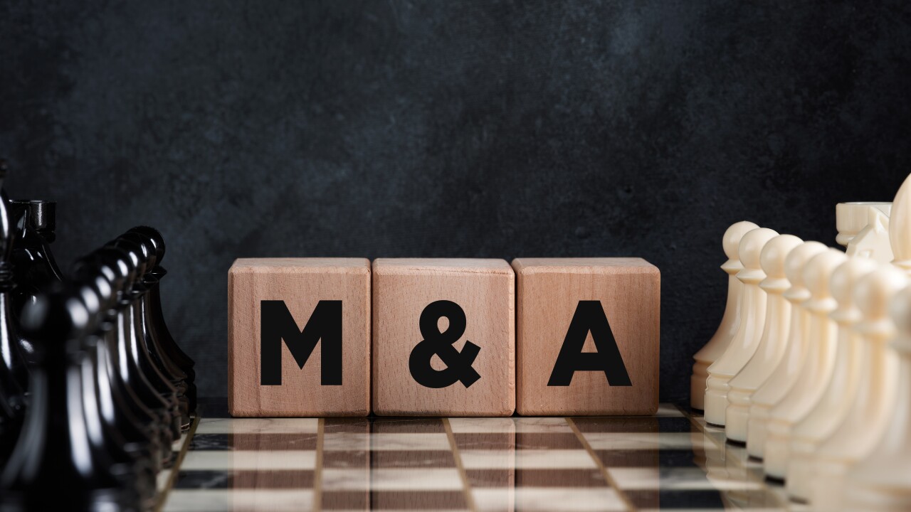 A chessboard with plastic black and white pieces arranged on either side displays three wooden blocks in the middle with the letters "M&A"