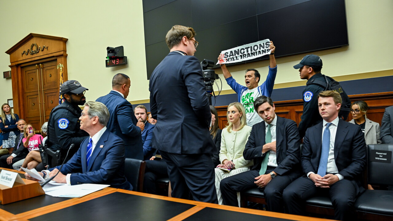 A picture of a demonstrator holding a protest sign as Scott Bessent, US treasury secretary, testified at a hearing in Washington, DC, on Tuesday.
