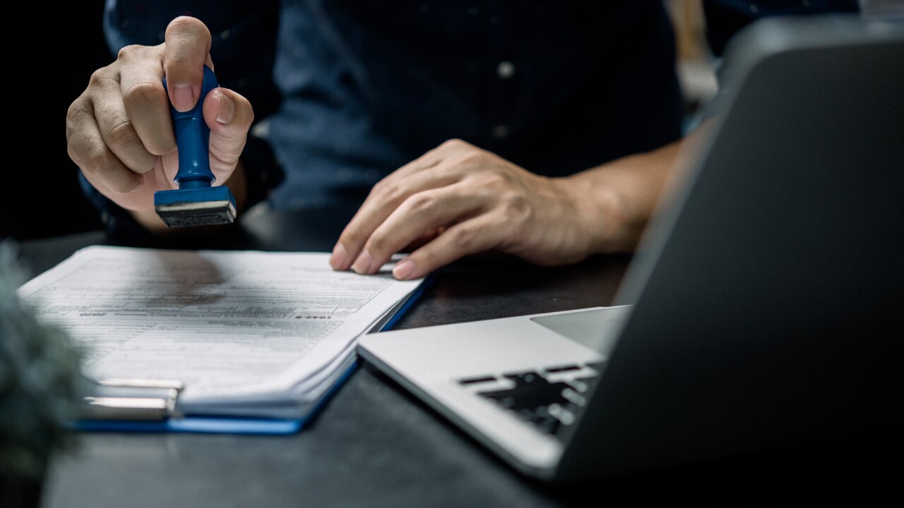 Man stamping approval of work finance banking or investment marketing documents on desk.