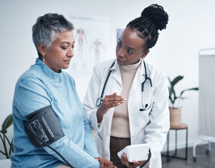 Female doctor taking blood pressure of female patient