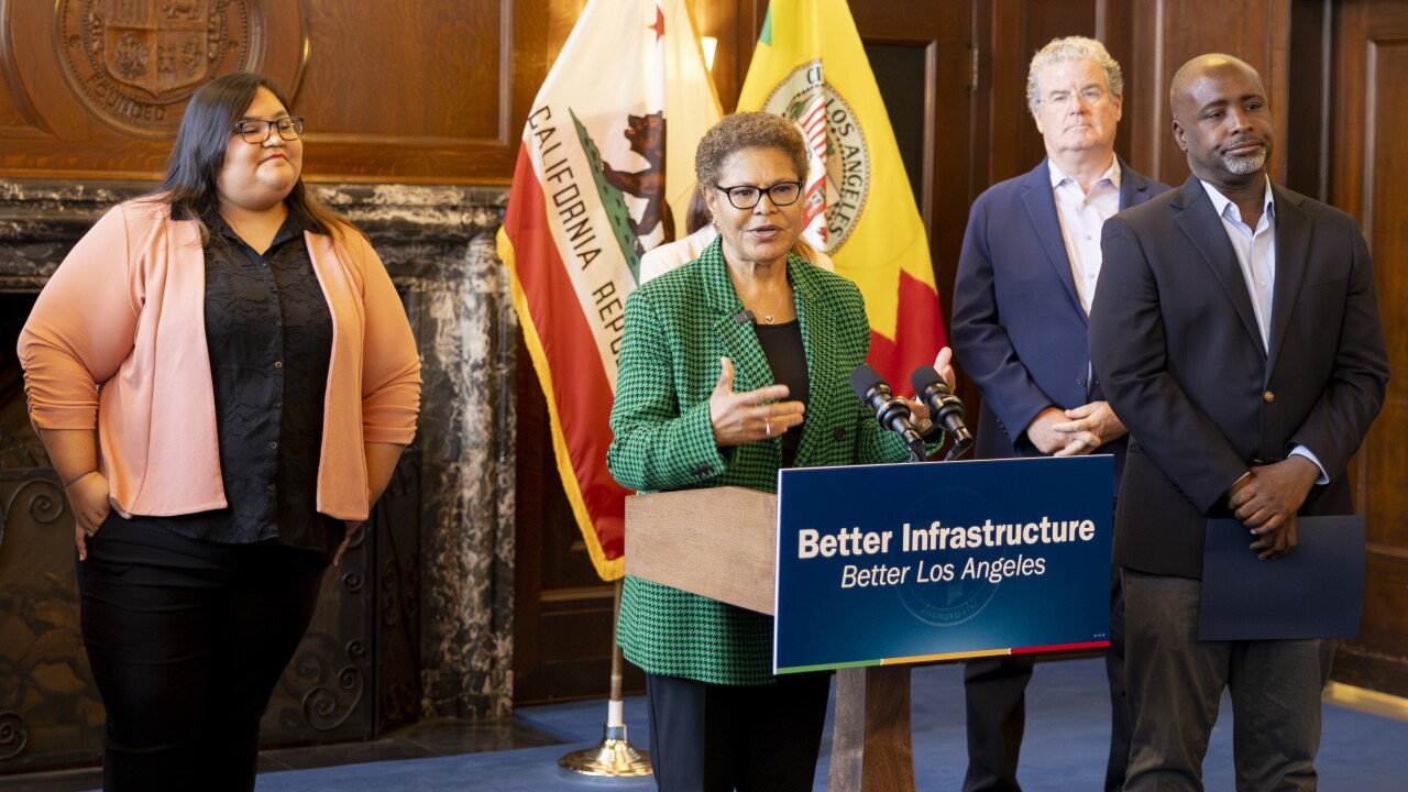 Los Angeles Mayor Bass behind podium flanked by three people stand nearby