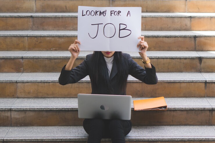 Woman holding up a sign looking for a job.