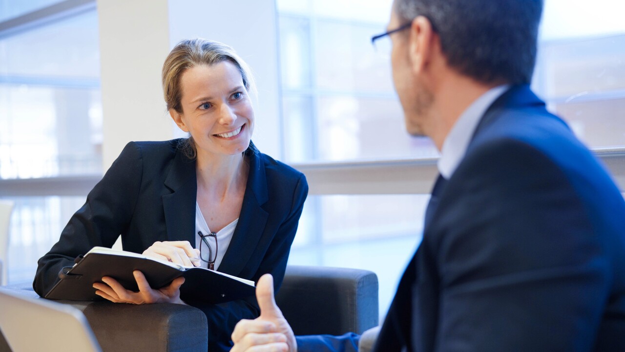 Woman talking with man, smiling, writing in notebook