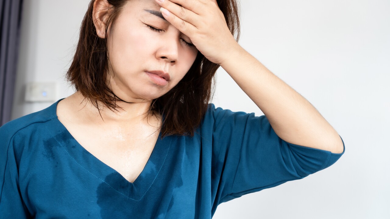 A woman is sweating with her hand on her forehead.