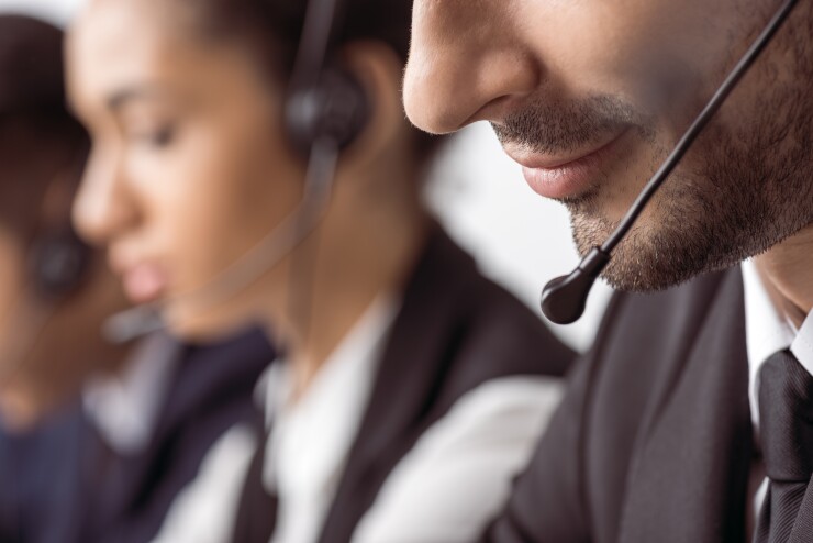 Close-up image of two workers, wearing headsets, at a call center.