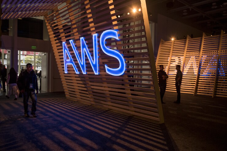 Attendees walk past a signage for Amazon Web Services (AWS) Summit in San Francisco, California, U.S., on Wednesday, April 19, 2017. Amazon.com Inc. Web Services chief executive officer Andy Jassy is leading a push into artificial intelligence to boost Amazon's cloud computing, which commands about 45 percent of the market for infrastructure as a service, where companies buy basic computing and storage power from the cloud. Photographer: David Paul Morris/Bloomberg