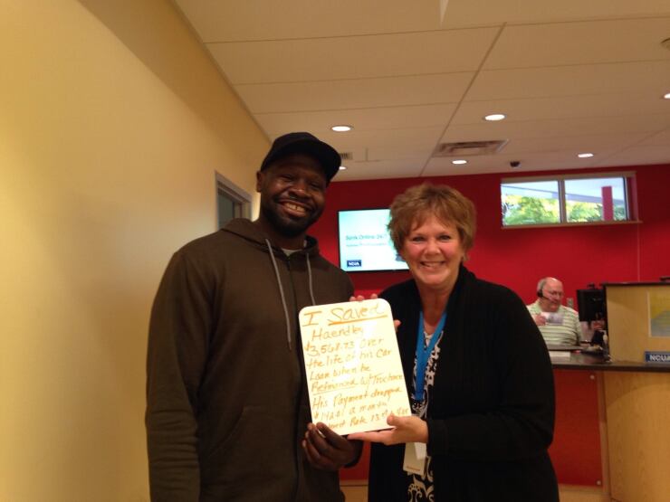 A TruChoice Federal Credit Union employee, right, poses with a member while showing off a sign detailing how much the member saved on a car loan.