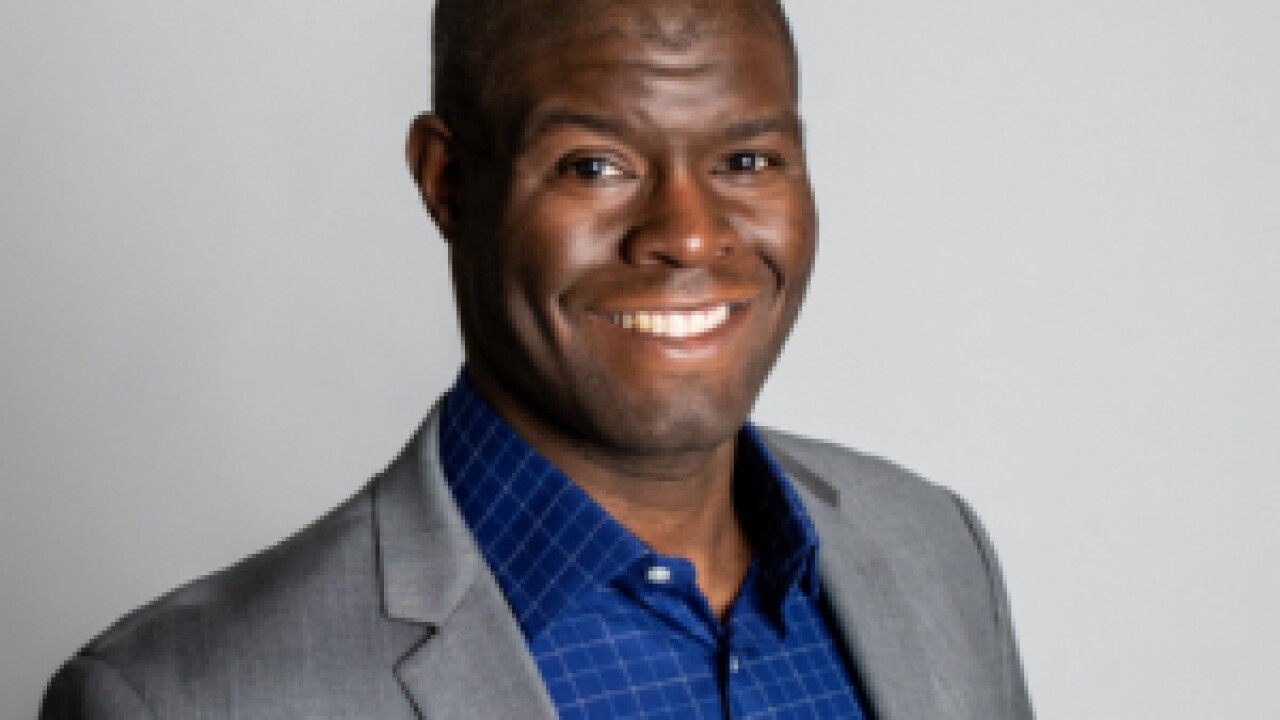 A man dressed in a suit coat smiling for a photo.