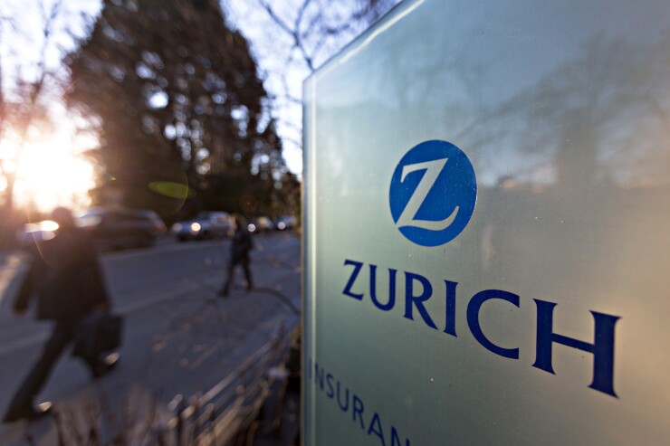 A sign that reads Zurich with blurred people walking in the background