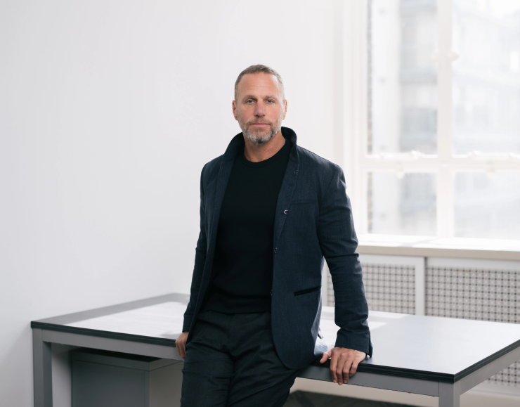Propel Holdings CEO Clive Kinross leans against table in well-lit room for a headshot.
