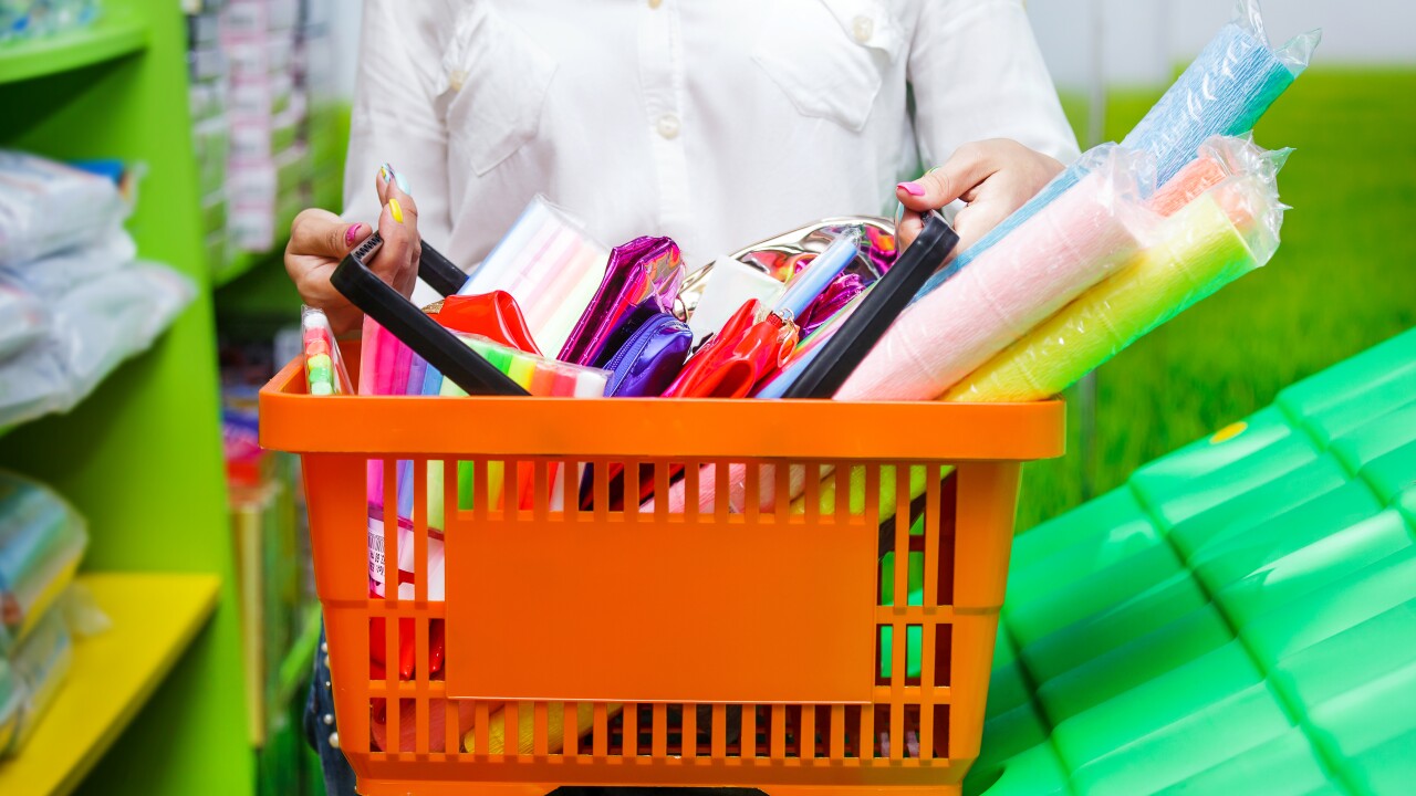 Woman holding shopping basket full of school supplies