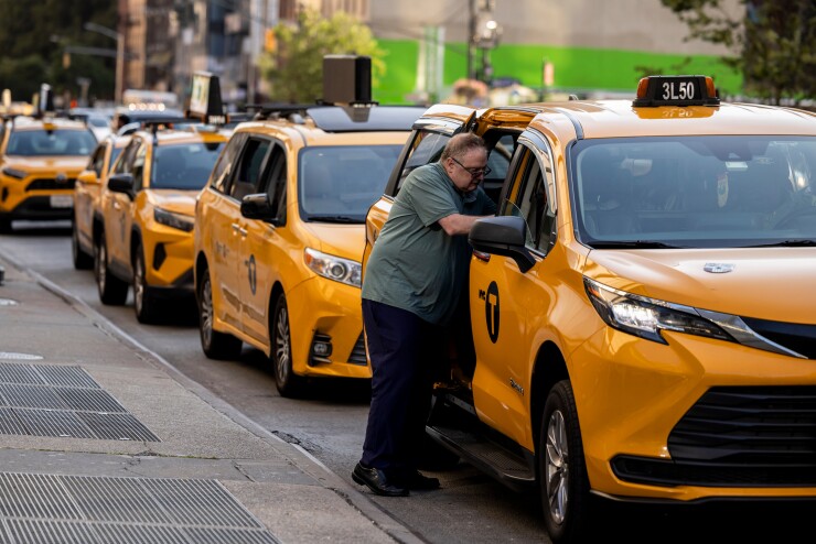 A line of yellow taxis with a person leaning into the first car.