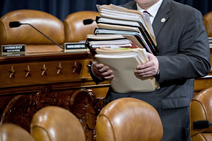 A staff member carries documents through the House Ways and Means Committee hearing room before the start of a markup hearing on the Tax Cut and Jobs Act.