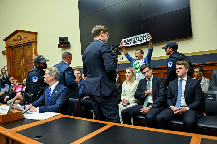 A picture of a demonstrator holding a protest sign as Scott Bessent, US treasury secretary, testified at a hearing in Washington, DC, on Tuesday.