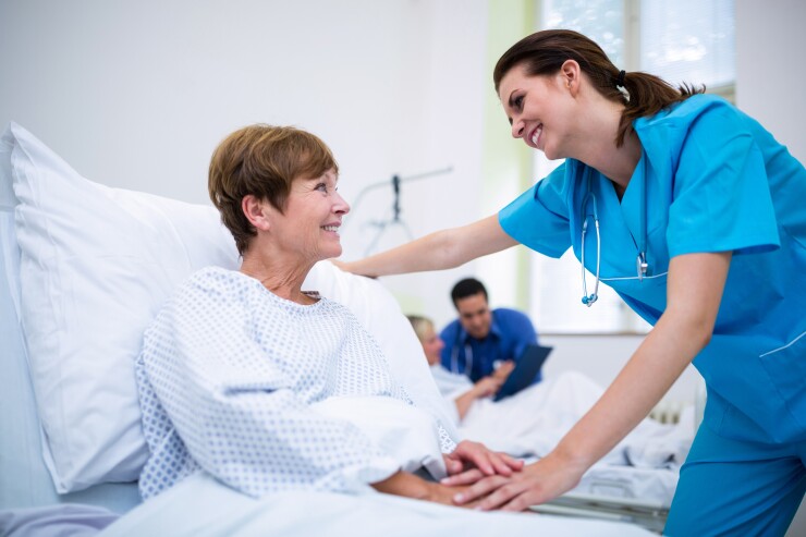 Healthcare professional checking on patient in hospital bed