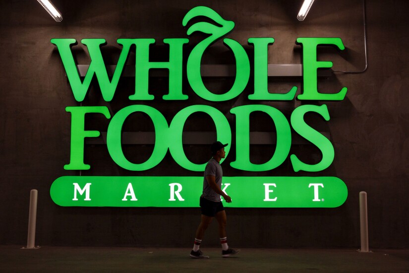 A pedestrian walks past Whole Foods Market signage outside a store in downtown Los Angeles.