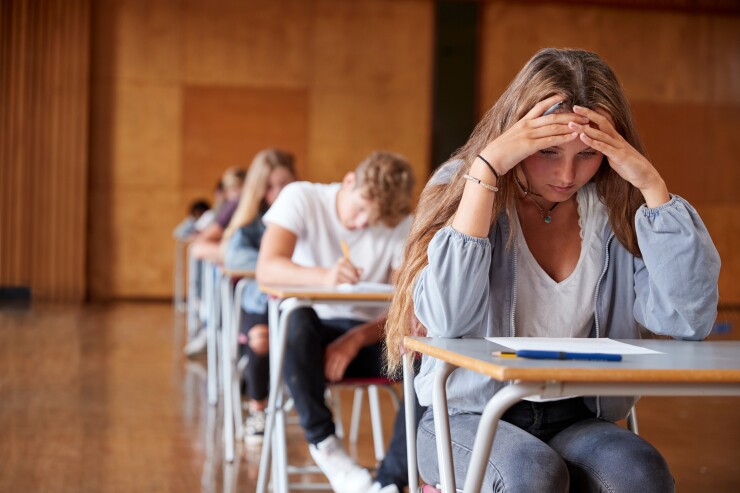 Highschool student sitting at a desk with her head in her hands