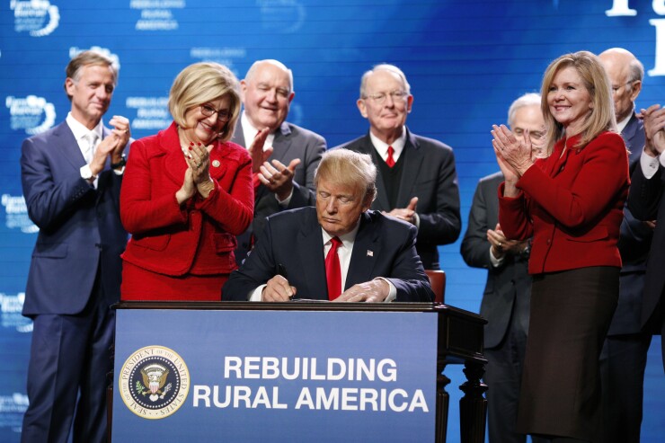 President Donald Trump signs an executive order, expanding rural broadband access to towers on federal lands, during the annual American Farm Bureau Federation conference in Nashville.