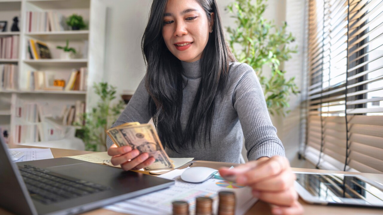 Woman working on computer counting money