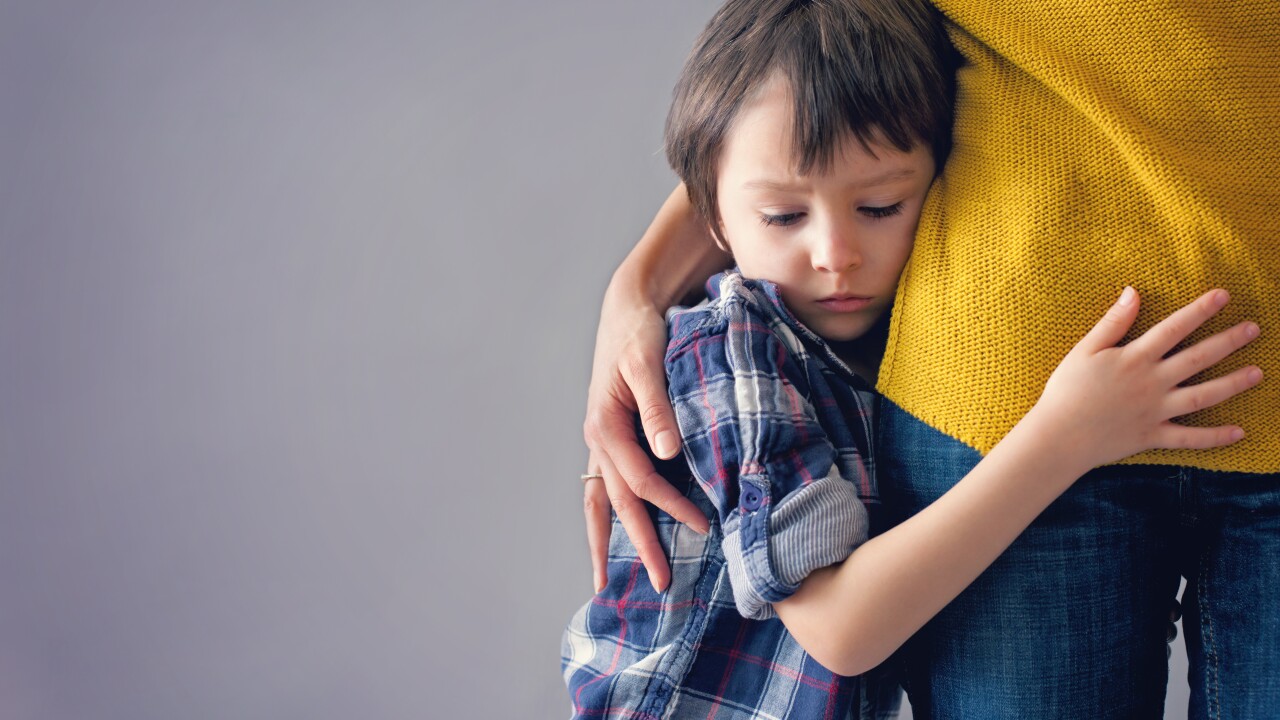 A young boy clings to his mother.