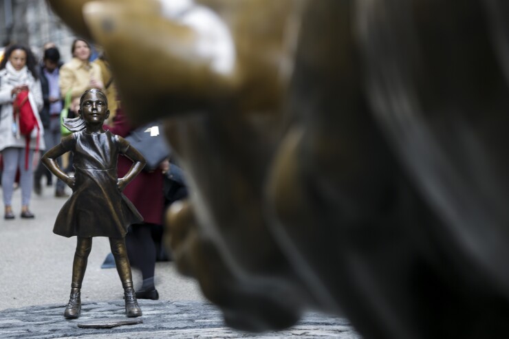 The Fearless Girl statue faces down the Charging Bull sculpture in the Financial District of New York.