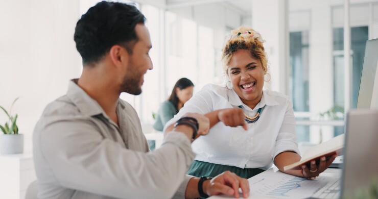 Two employees, happy, laughing, fist bump
