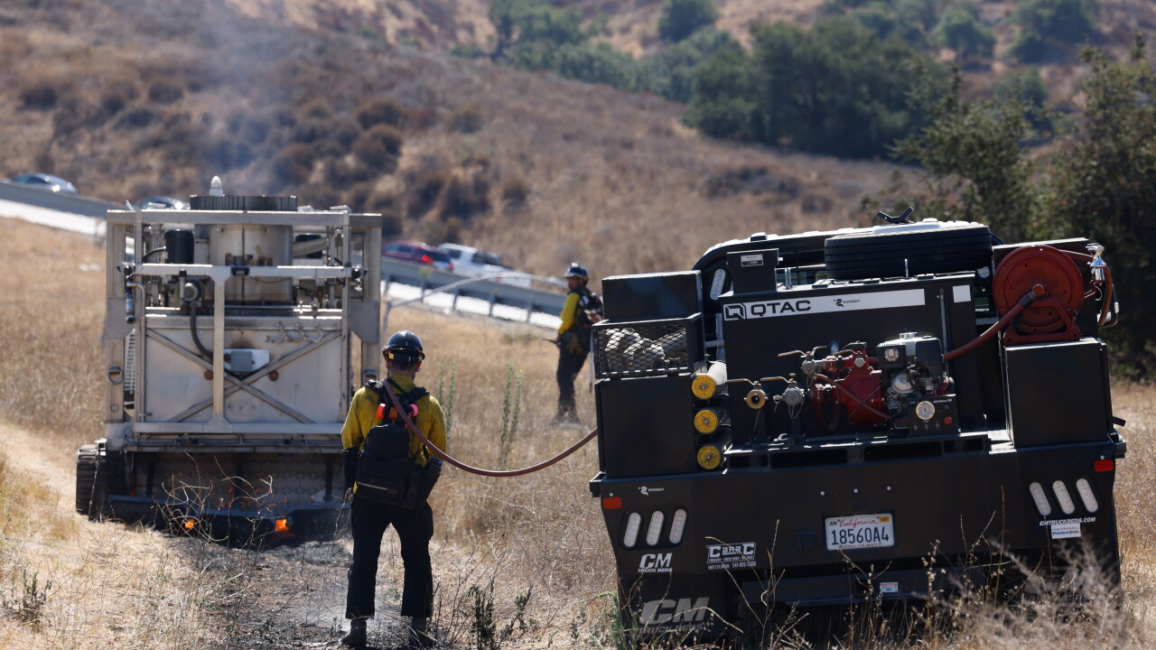 Technician operating BurnBot for prescribed burn demo on a hillside