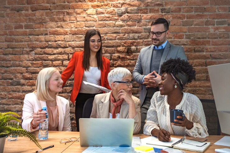 Group of employees, various ages, sitting, standing, talking, smiling