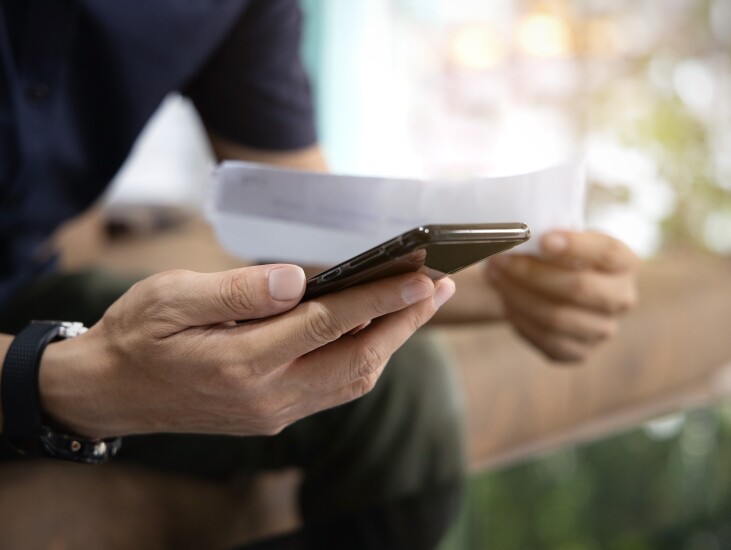 Close up Man checklist using bank of credit card by mobile phone and pay bills in the office