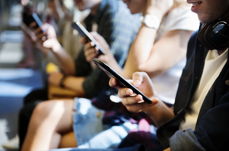 Young adults using cellphones in the subway.