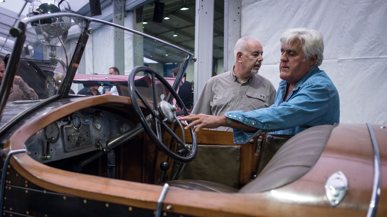 Jay Leno, right, views a 1925 Renault SA 40 CV Torpedo Skiff vehicle at the 2019 Pebble Beach Concours d'Elegance in California.