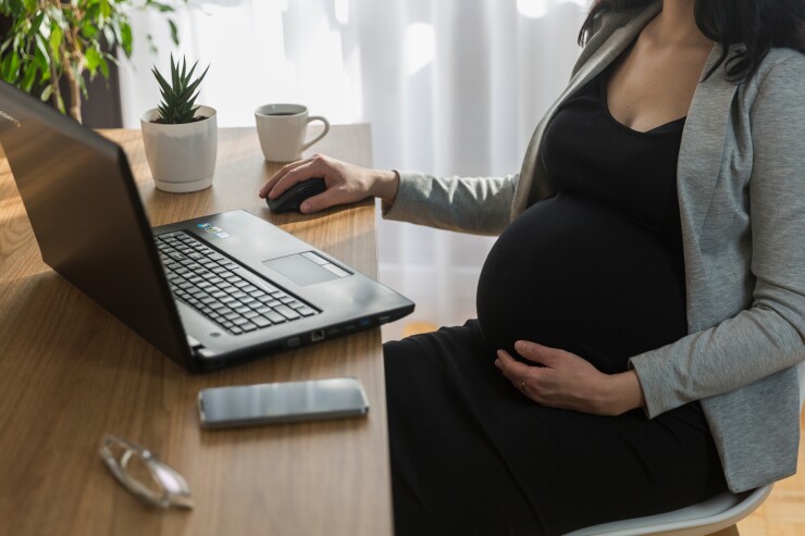 Pregnant woman sitting at desk, holding belly
