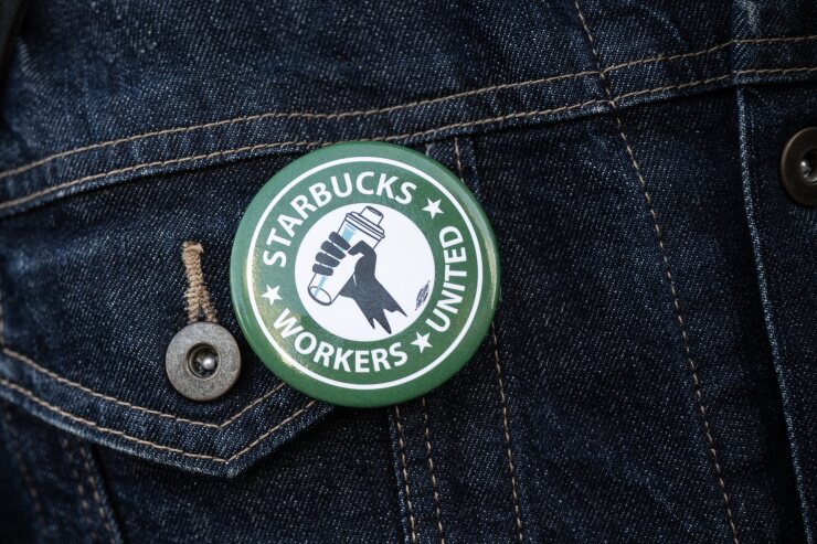 "Starbucks Workers United" pin on a dark jean jacket.