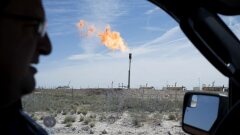 A gas flare is seen through the window as a Royal Dutch Shell Plc representative drives near Mentone, Texas.