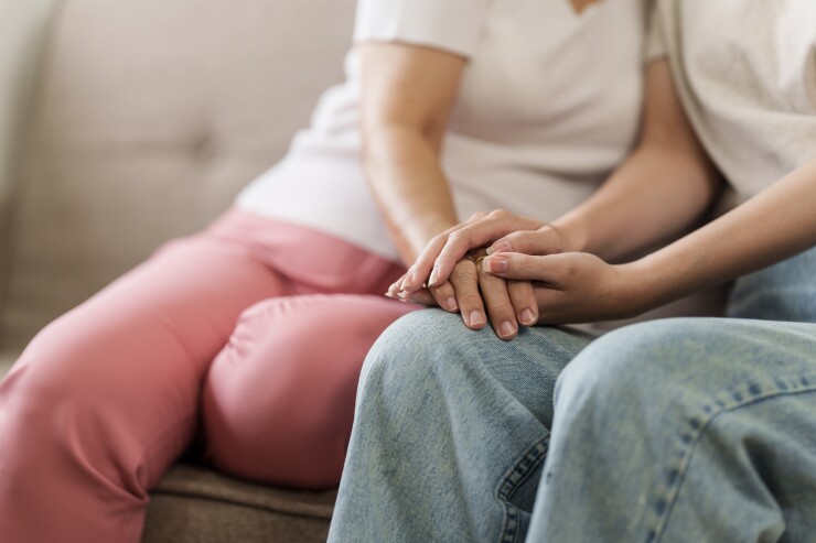 Two women sitting on the couch holding hands