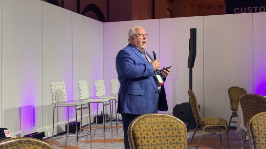 Photo of a man in a blue-checked suit holding a microphone.