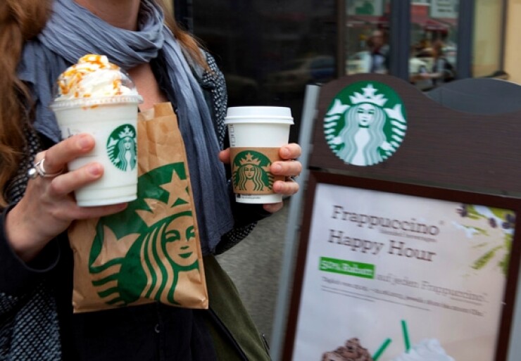 A customer holds Starbucks Corp. beverages as she exits one of the company's coffee shops in Berlin, Germany, on Tuesday, May 28, 2013. Starbucks, the world's biggest coffee-shop operator, reported fiscal second-quarter profit in April that met analysts' estimates as U.S. customer traffic improved while sales stagnated in Europe. Photographer: Krisztian Bocsi/Bloomberg