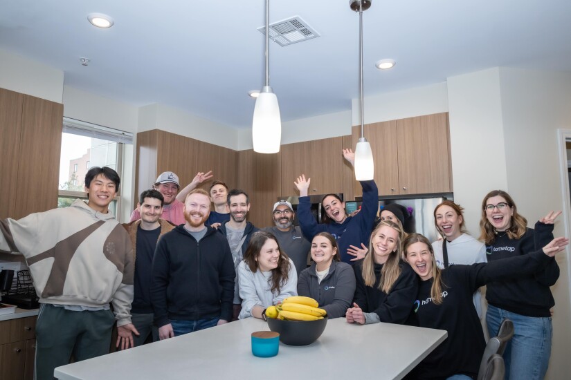 Group of Hometap employees wearing dark blue crewnecks in an empty new kitchen.