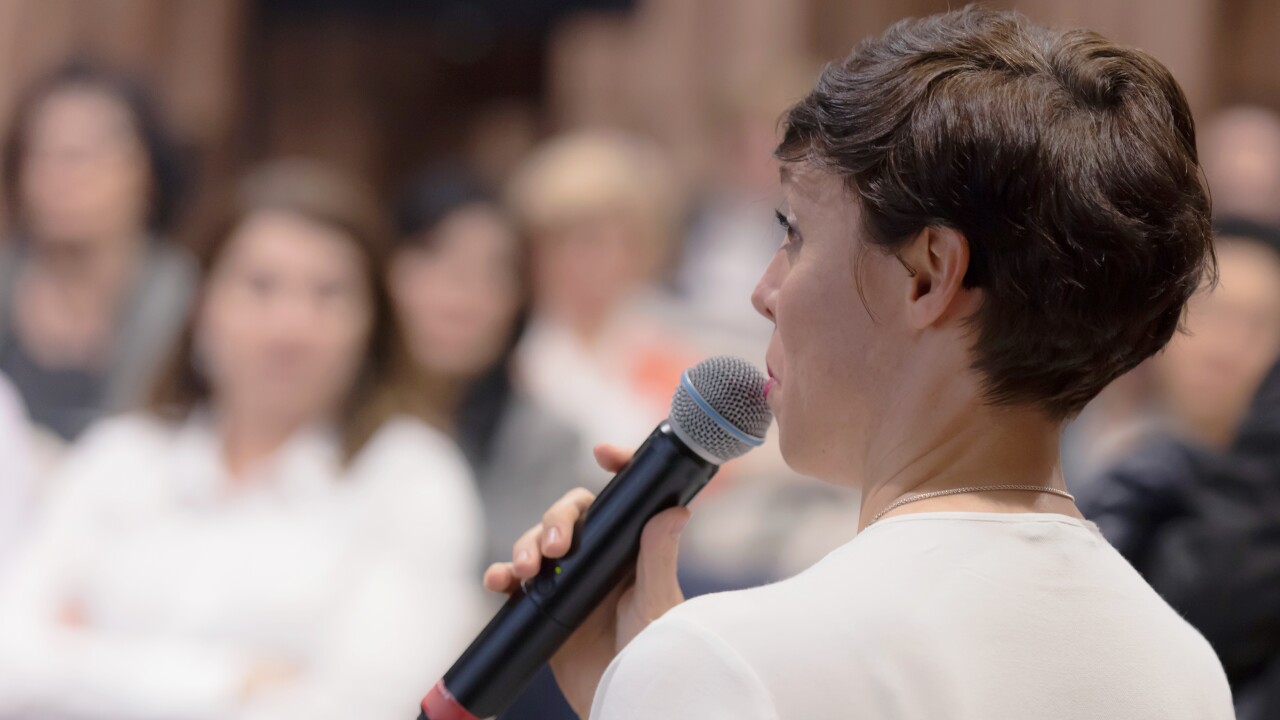 Woman holding microphone speaking on stage