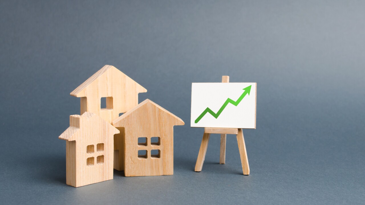 Wooden figures of houses and a poster with green arrow up. Increase liquidity and attractiveness of assets. Raising the rent or cost of buying a home.The concept of real estate value growth.