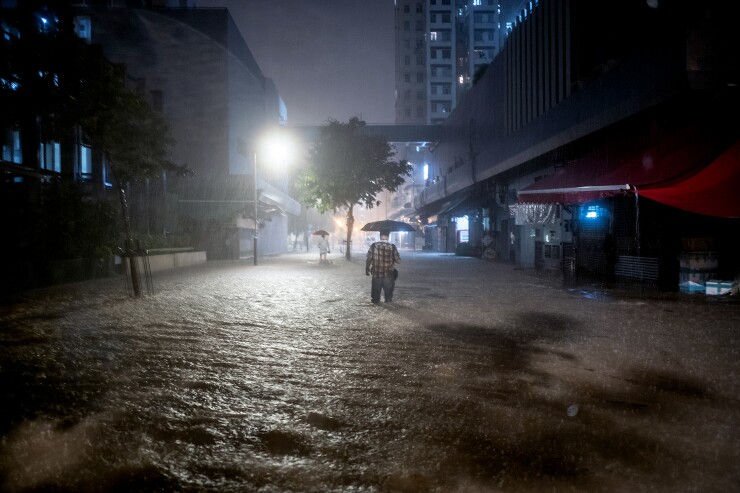 A person with an umbrella walking on a flooded street.