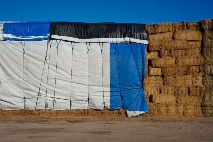 Bales of hay partially covered by tarps in Blythe, California, US, on Monday, Oct. 17, 2022. California water agencies that rely on the parched Colorado River said they can reduce their use by one-tenth starting in 2023 in response to calls for cuts from the federal government, reported the AP. Photographer: Bing Guan/Bloomberg
