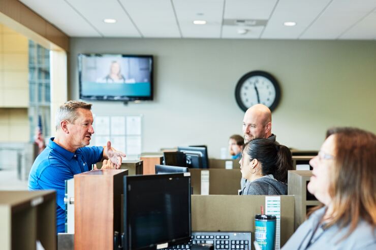 Gary Swindler, left, the next CEO of WSECU, meets with tellers at the credit union's Olympia, Wash. branch.