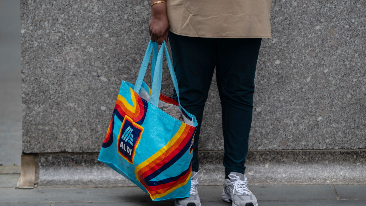 A picture of a shopper carrying a bag from Aldi's grocery store.