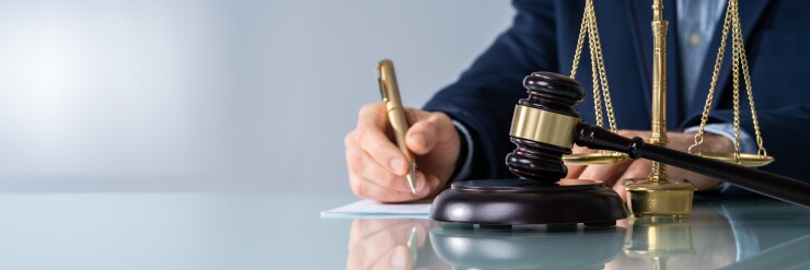Male Judge Signing Document At Desk