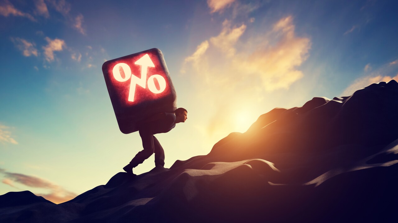 Man carrying heavy stone with growing interest rate symbol