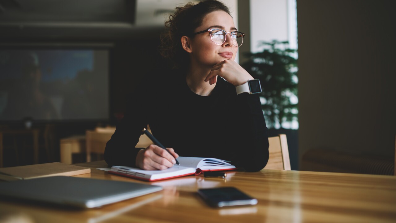 A woman is writing in her notebook, deep in thought.