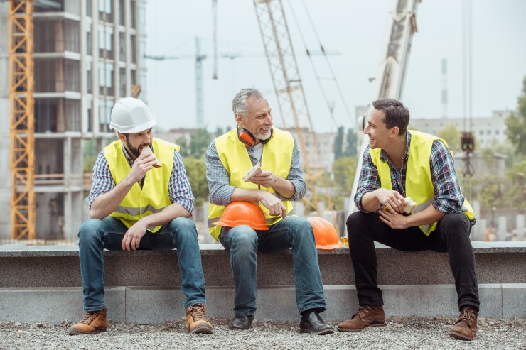 Construction workers sitting and talking near worksite